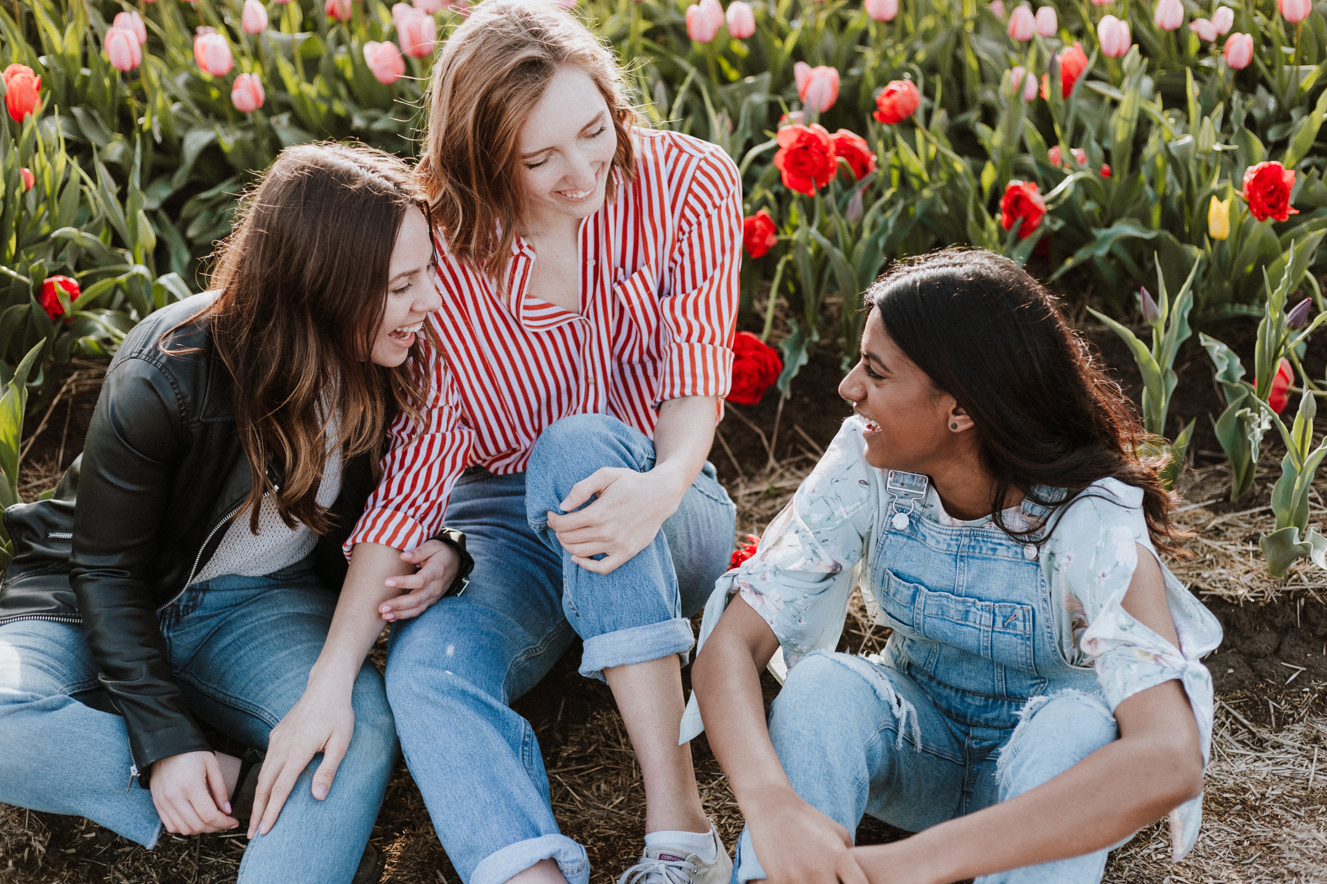 Three young women sat among flowers.
